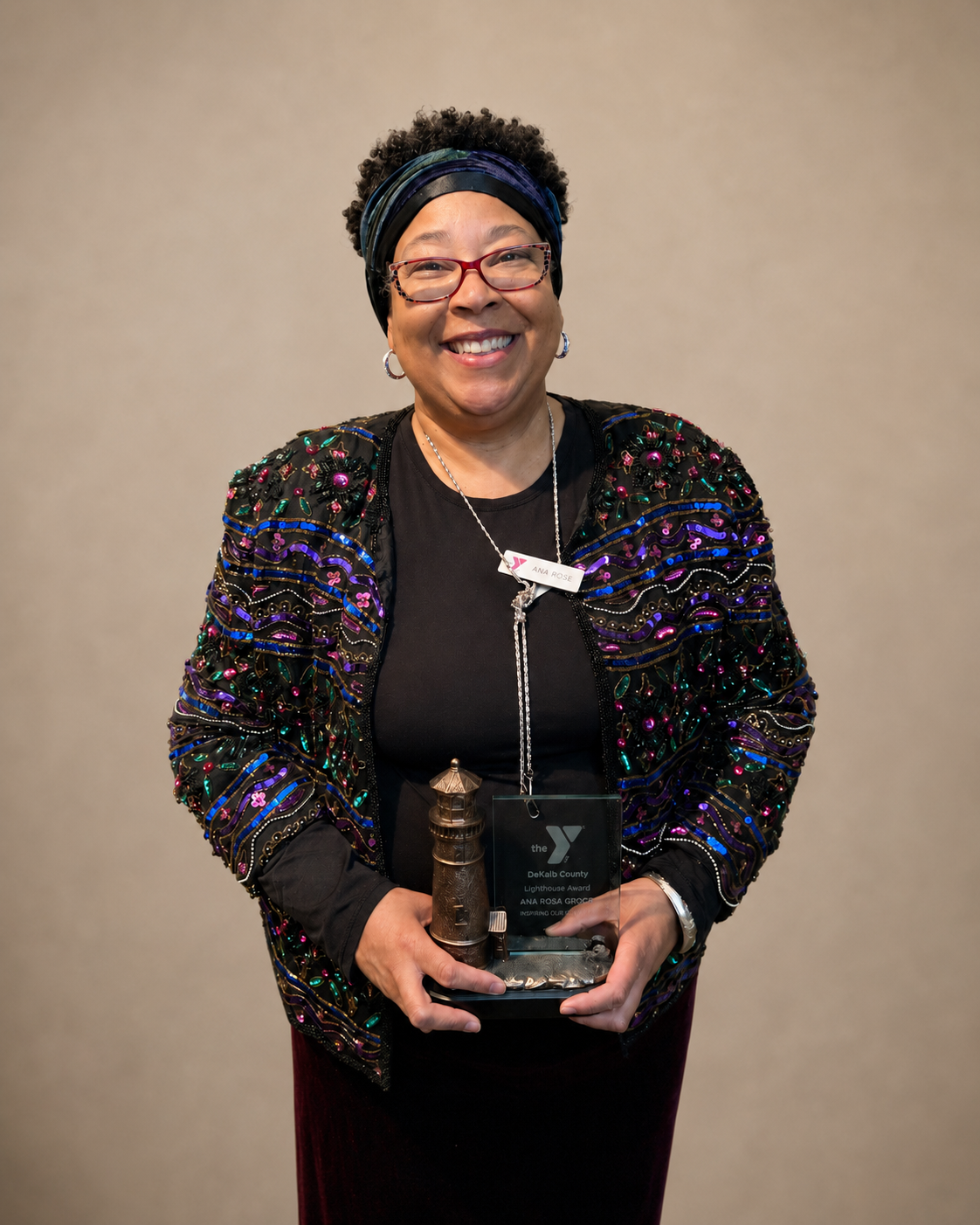 Coach Ana Rose smiling while holding a Lighthouse Award